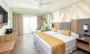 Et hotellrom med to senger, en sofa og en dekorativ veggdesign. (AI-generert tekst)