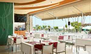 En restaurant med glassvegger som vender mot et bassengområde. (AI-generert tekst)