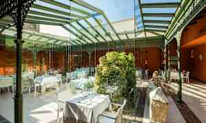 Innendørs servering med glassvegger og tak, dekorert med grønt og bord. (AI-generert tekst)