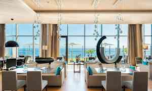 Moderne restaurant med store vinduer mot havet. (AI-generert tekst)