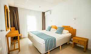 Et hotellrom med to enkeltsenger, bambusmøbler og hvite vegger. (AI-generert tekst)