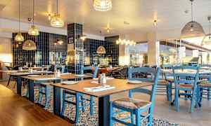 En restaurant med bord og blå stoler. (AI-generert tekst)