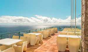 Terrasse med bord og stoler ved havet. (AI-generert tekst)