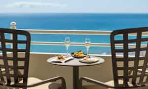 To tallerkener med mat og to glass med drikke på et bord med havutsikt. (AI-generert tekst)