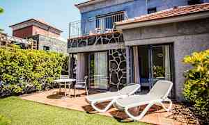 Bilde av en terrasse med solsenger og sittemøbler ved et hus. (AI-generert tekst)