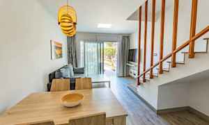 En stue med bord, stoler, en sofagruppe og en trapp. (AI-generert tekst)