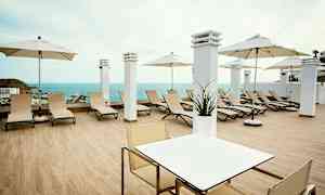 En terrasse med solsenger, parasoller og utsikt over havet. (AI-generert tekst)