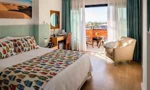 Hotellrom med dobbeltseng, sittegruppe og en balkong med utsikt. (AI-generert tekst)