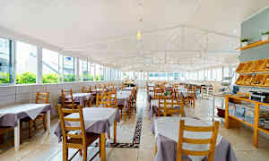 En romslig restaurant med bord dekket med lilla og hvite duker. (AI-generert tekst)