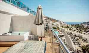 En balkong med sittegruppe og utsikt over en by og havet. (AI-generert tekst)