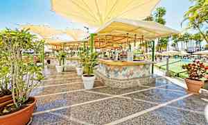 Utendørsmiljø med en bar og sitteplasser under store parasoller. (AI-generert tekst)