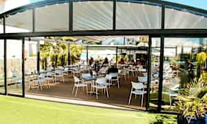 Bilde av en restaurant med sitteområde utendørs og glassvegger. (AI-generert tekst)