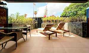 En terrasse med solsenger, bord og stoler samt omgitt av planter. (AI-generert tekst)