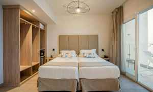 To enkeltsenger med beige hodegjerde og nattbord på hver side. (AI-generert tekst)