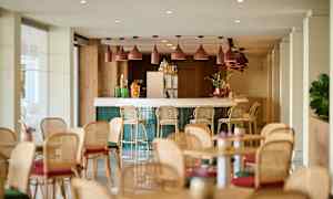 En lys og moderne innendørs bar med barkrakker og bord rundt omkring. (AI-generert tekst)