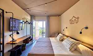 Hotellrom med to enkeltsenger, arbeidsbord med lampe og TV, samt balkong med utsikt. (AI-generert tekst)