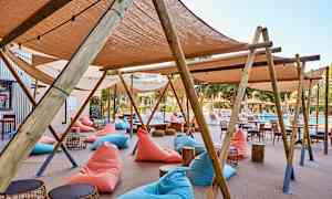 Utendørsområde med strandstoler, tremøbler og solsenger nær et basseng. (AI-generert tekst)