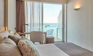 Et hotellrom med utsikt over havet gjennom vinduet. (AI-generert tekst)