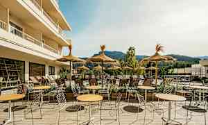 Utendørsområde med bord, stoler og parasoller ved en solrik terrasse. (AI-generert tekst)