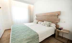 To enkeltsenger med grønne sengetepper i et lyst rom. (AI-generert tekst)