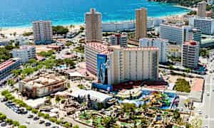 Luftfoto av en kystby med hotellbygninger, strand og et fornøyelsesområde. (AI-generert tekst)