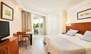 Bilde av et hotellrom med to enkeltsenger, et skrivebord med stoler og en balkong. (AI-generert tekst)