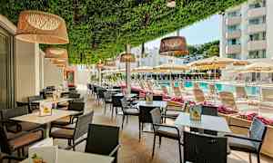 Uteservering med bord og stoler, ved siden av et basseng og solsenger under parasoller. (AI-generert tekst)