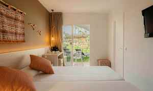 Et hotellrom med to senger, dekorativ veggdekorasjon og en terrasse med utsikt over grøntområde. (AI-generert tekst)