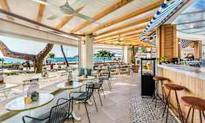 En utendørs bar med sitteplasser, havet synlig i bakgrunnen. (AI-generert tekst)