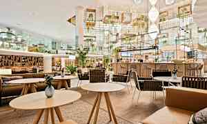 Moderne og elegant innredet kafé med sittegrupper og planter. (AI-generert tekst)