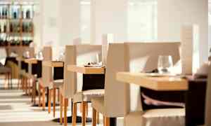 Interiør av en lys og elegant restaurant med dekkede bord og stoler. (AI-generert tekst)