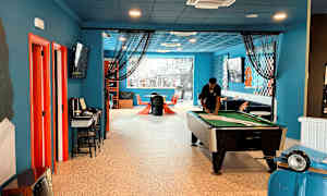 Et innendørs rom med et biljardbord, sitteplasser og dekorasjoner i fargerike detaljer. (AI-generert tekst)