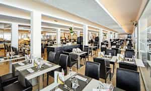 Et lyst og moderne restaurantområde med dekkede bord og svarte stoler. (AI-generert tekst)