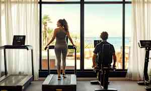 Treningsstudio med utsikt over havet gjennom store vinduer. (AI-generert tekst)