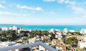 Utsikt over en kystby med bygninger, trær og havet i bakgrunnen. (AI-generert tekst)