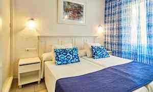 Bilde av soverom med to enkeltsenger, blå pute og sengeteppe, samt blå gardiner. (AI-generert tekst)