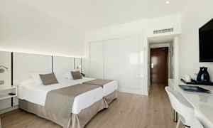 Et hotellrom med to enkeltsenger, skrivebord og TV. (AI-generert tekst)