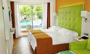 Hotellrom med dobbeltseng, grønn hodegavl og utsikt til et utendørs svømmebasseng. (AI-generert tekst)