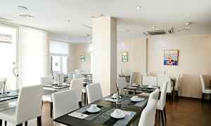 Et lyst restaurantområde med hvite stoler og mørke bord, dekket med servise og dekorasjoner. (AI-generert tekst)