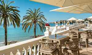 En terrasse med utsikt over havet, solsenger og parasoller. (AI-generert tekst)