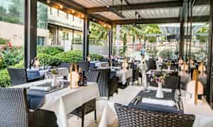 Utendørsrestaurant med oppdekkede bord og dekorerte stoler. (AI-generert tekst)