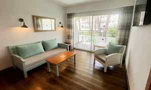 En sittegruppe med sofabord og stoler, samt et glassvindu som fører til en balkong. (AI-generert tekst)