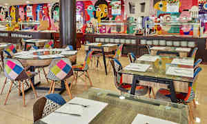 Innredning av en restaurant med fargerike stoler og dekorerte vegger. (AI-generert tekst)