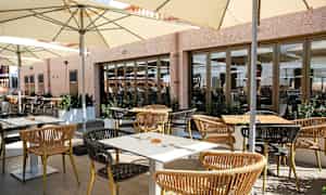 Uteservering med bord, stoler og parasoller. (AI-generert tekst)