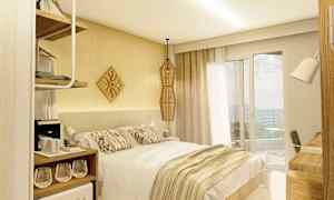 Et hotellrom med en dobbeltseng, lyst interiør og et vindu som vender ut mot en balkong. (AI-generert tekst)