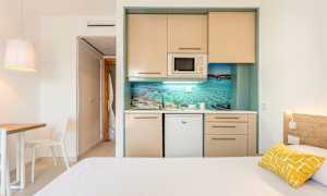 Et enkelt hotellrom med et lite kjøkken og en seng. (AI-generert tekst)