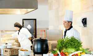 To kokker ved en serveringsstasjon med grønnsaker og mat. (AI-generert tekst)