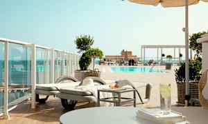 Utsikt over et basseng med solsenger og parasoller. (AI-generert tekst)