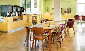 En spisesal med dekket bord og fargerike stoler. (AI-generert tekst)