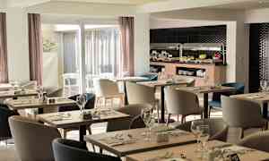 Bildet viser en moderne restaurant med bord og stoler, samt en buffet med mat. (AI-generert tekst)